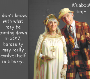 Errol and Rochelle standing in silly costumes, Rochelle looking like a goddess woman in a wedding dress, and Errol, in a plaid costume resembling Charlie Chaplin. The text to the upper-right of Errol reads "It's about time" and the text to the left of Rochelle reads "I don't know, with what may be coming down in 2017, humanity may really evolve itself in a hurry."