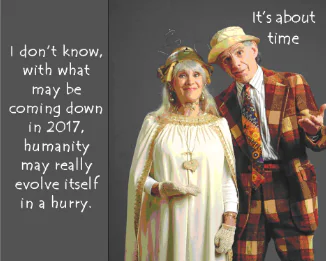 Errol and Rochelle standing in silly costumes, Rochelle looking like a goddess woman in a wedding dress, and Errol, in a plaid costume resembling Charlie Chaplin. The text to the upper-right of Errol reads "It's about time" and the text to the left of Rochelle reads "I don't know, with what may be coming down in 2017, humanity may really evolve itself in a hurry."